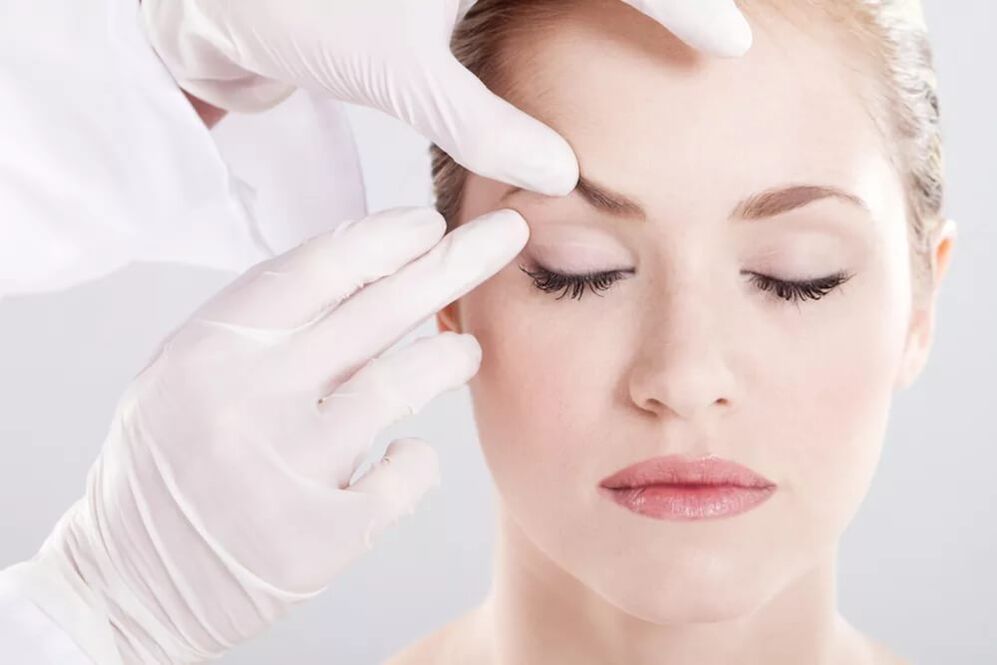 The beautician examines the skin around the eyes around the eyes